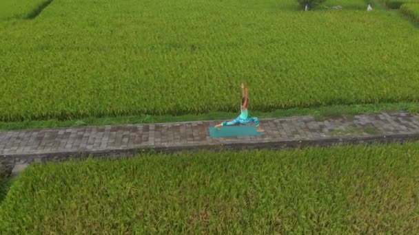 Aerial Slowmotion shot di una giovane donna che pratica yoga su una bella risaia — Video Stock