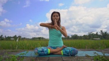 Bali bir şekilde Muladhara çakra için meditasyon yapan genç bir kadının Slowmotion steadicam çekim