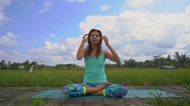 Bali bir şekilde Muladhara çakra için meditasyon yapan genç bir kadının Slowmotion steadicam çekim