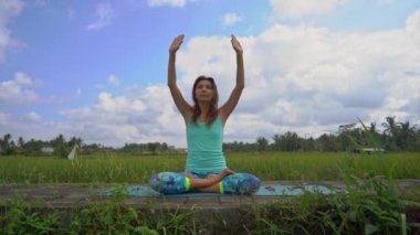 Bali bir şekilde Muladhara çakra için meditasyon yapan genç bir kadının Slowmotion steadicam çekim