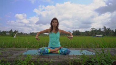 Bali bir şekilde Muladhara çakra için meditasyon yapan genç bir kadının Slowmotion steadicam çekim