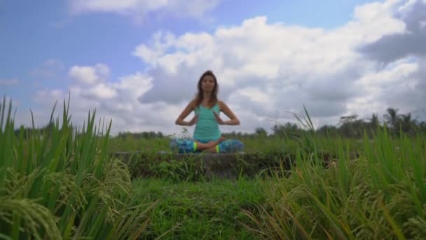 バリの方法でムラダラチャクラのために瞑想をしている若い女性のスローモーションステディカムショット — ストック動画