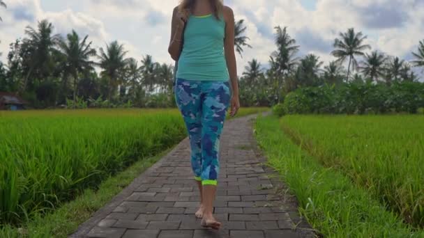 慢动作稳定拍摄一个年轻女子与瑜伽数学走过美丽的稻田 — 图库视频影像