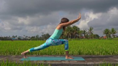 Güzel bir pirinç tarlasında yoga yapan genç bir kadının slowmotion steadicam çekim