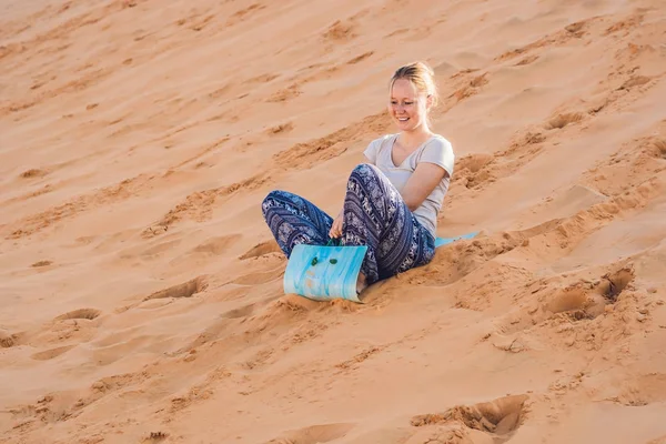 Junge Frau rollt auf Schlitten in der Wüste — Stockfoto