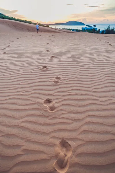 Footprints in the sand in the red desert at Sunrise