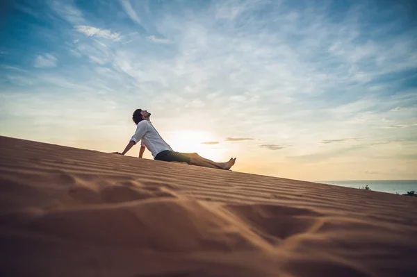 Человек сидит на песке в пустыне — стоковое фото