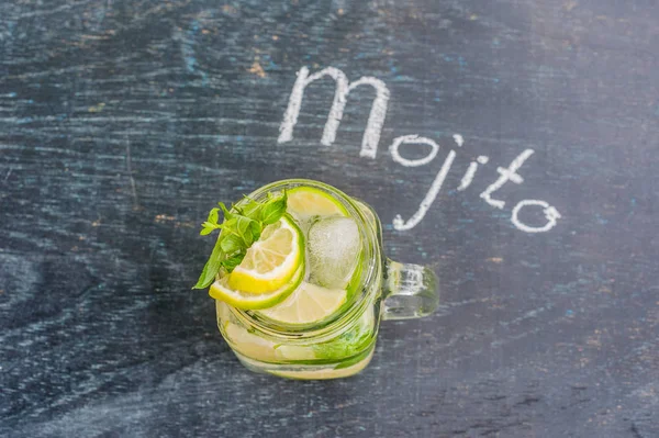 Ποτήρι mojito με λάιμ και μέντα Φράζω κύβου πάγου σε σκούρο φόντο ξύλου — Φωτογραφία Αρχείου