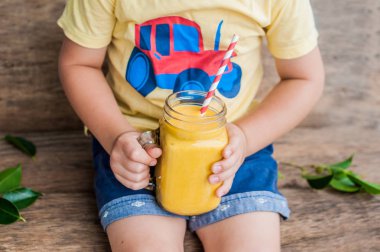 Çocuk içme sulu güler yüzlü mango mason cam eski ahşap arka plan üzerinde çizgili kırmızı saman ile üzerinden. Sağlıklı yaşam konsepti, kopya alanı