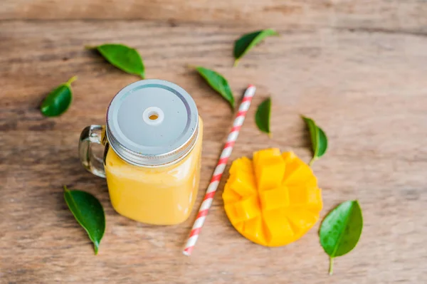 Juicy smoothie from mango in glass mason jar with striped red straw on old wooden background. Healthy life concept, copy space — Stock Photo, Image