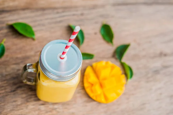 Juicy smoothie from mango in glass mason jar with striped red straw on old wooden background. Healthy life concept, copy space — Stock Photo, Image