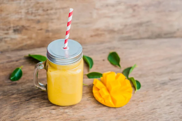 Cerdas smoothie dari mangga dalam botol tukang kaca dengan bergaris merah jerami pada latar belakang kayu tua. Konsep hidup sehat, menyalin ruang — Stok Foto