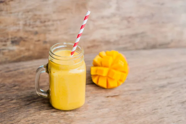 Juicy smoothie from mango in glass mason jar with striped red straw on old wooden background. Healthy life concept, copy space — Stock Photo, Image