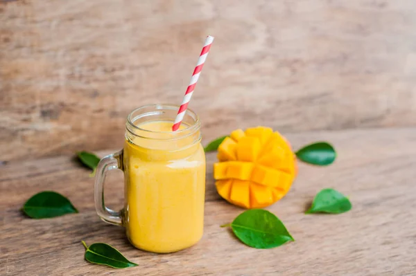 Juicy smoothie from mango in glass mason jar with striped red straw on old wooden background. Healthy life concept, copy space — Stock Photo, Image