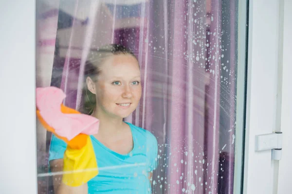 Hermosa doncella haciendo las tareas domésticas mientras usa un spray, lavando ventanas — Foto de Stock