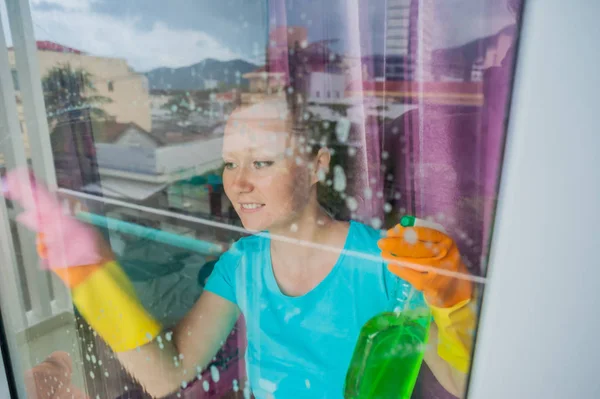 Hermosa doncella haciendo las tareas domésticas mientras usa un spray, lavando ventanas — Foto de Stock