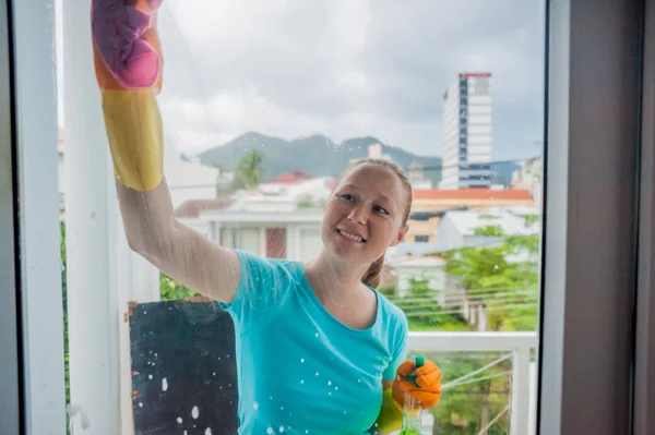 Hermosa doncella haciendo las tareas domésticas mientras usa un spray, lavando ventanas — Foto de Stock