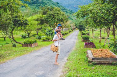 Baba ve oğul manzaralı bir yolda yürürken dikiz