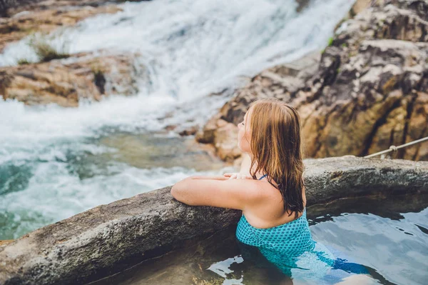 Геотермальный курорт. Женщина отдыхает в бассейне с горячей водой на фоне водопада — стоковое фото