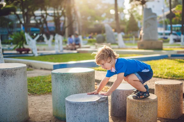 Sevimli sarışın çocuk parkta taşları tırmanıyor. Çocukluk, kavram — Stok fotoğraf
