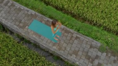 Güzel bir pirinç tarlasında yoga yapan genç bir kadının Havadan Slowmotion çekimi
