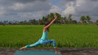 Güzel bir pirinç tarlasında yoga yapan genç bir kadının slowmotion steadicam çekim