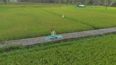 Bali usulü Muladhara çakrası için meditasyon yapan genç bir kadının hava fotoğrafı.