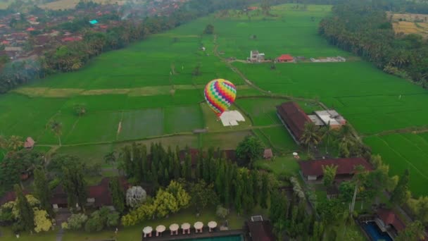 Letecký záběr horkovzdušného balónu, který letí nad velkým zeleným rýžovým polem. Cestovat na Bali. — Stock video