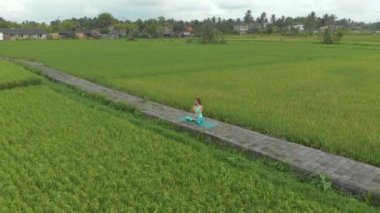 Bali usulü Muladhara çakrası için meditasyon yapan genç bir kadının hava fotoğrafı.