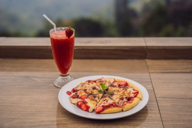 Delicious strawberry pizza on a balinese tropical nature background. Bali island, Indonesia clipart