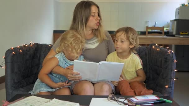 Un professeur, un tuteur pour l'école à domicile. un professeur ou une mère à la table avec une petite fille et un garçon. Concept d'enseignement à domicile — Video