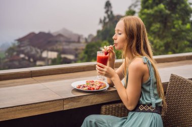 Kadın, tropik bale arka planında lezzetli çilekli pizza yiyor. Bali Adası, Endonezya