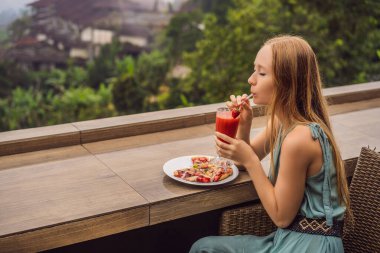 Kadın, tropik bale arka planında lezzetli çilekli pizza yiyor. Bali Adası, Endonezya