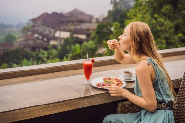 Kadın, tropik bale arka planında lezzetli çilekli pizza yiyor. Bali Adası, Endonezya