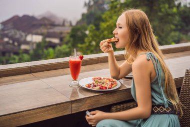 Kadın, tropik bale arka planında lezzetli çilekli pizza yiyor. Bali Adası, Endonezya