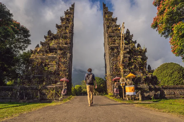 Турист проходит через традиционные балийские индуистские ворота Candi Bentar рядом с Бедугулом, озером Братан на острове Бали Индонезии. Отдых на Бали — стоковое фото