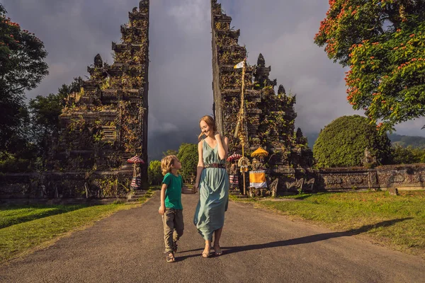 Μητέρα και γιος με τα πόδια μέσα από Παραδοσιακά Μπαλί ινδουιστική πύλη Candi Bentar κοντά στο Bedugul, Bratan λίμνη Μπαλί νησί Ινδονησία. Διακοπές στο Μπαλί. Ταξιδεύοντας με την έννοια των παιδιών — Φωτογραφία Αρχείου