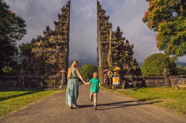 Anne ve oğlu, Endonezya 'daki Bratan Gölü Bali Adası yakınlarındaki geleneksel Hindu kapısı Candi Bentar' dan geçiyorlar. Bali 'de tatil. Çocuk konseptiyle seyahat etmek