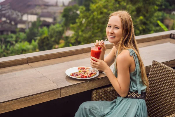 Kadın, tropik bale arka planında lezzetli çilekli pizza yiyor. Bali Adası, Endonezya