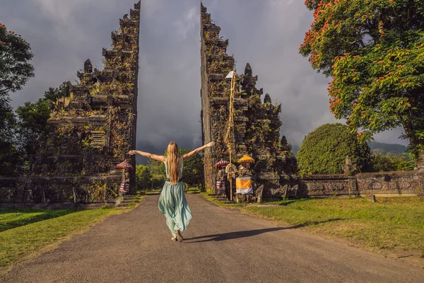 Turista mujer caminando a través de la tradicional puerta hindú balinesa Candi Bentar cerca de Bedugul, Bratan lago Bali isla Indonesia. Vacaciones en Bali — Foto de Stock