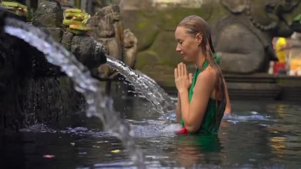 Filmagem em câmara lenta de uma jovem visitando as nascentes de azevinho na Indonésia. Tirta Empul nasce água benta na ilha de Bali — Vídeo de Stock