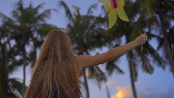Fotografía en cámara lenta de una mujer joven en una playa tropical con una cometa durante el atardecer — Vídeos de Stock