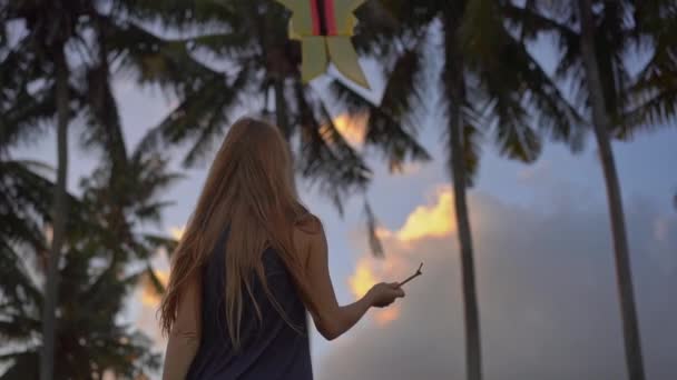 Fotografía en cámara lenta de una mujer joven en una playa tropical con una cometa durante el atardecer — Vídeos de Stock