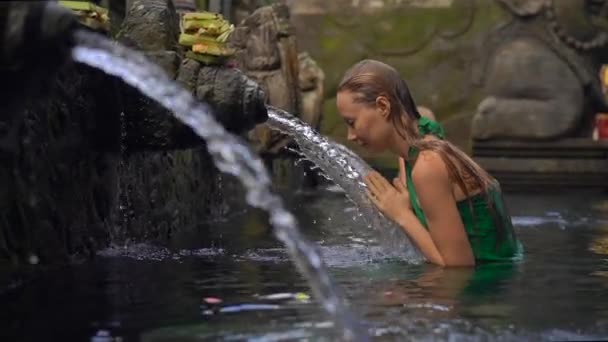 Slowmotion shot of a young woman visiting the holly springs in Indonesia. Tirta Empul holy water springs on the Bali island — ストック動画