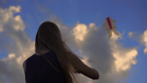 Slow motion shot van een jonge vrouw op een tropisch strand met een vlieger tijdens een zonsondergang — Stockvideo