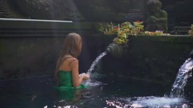 Endonezya 'daki Holly Springs' i ziyaret eden genç bir kadının yavaş çekimi. Tiran Bali adasındaki kutsal su kaynaklarını boşalttı
