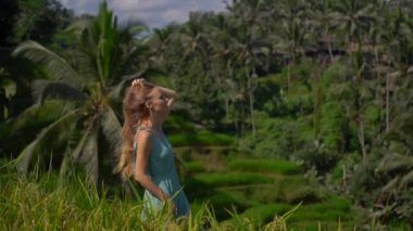Mavi elbiseli güzel bir genç kadının yavaş çekimleri Bali adasındaki Ubud köyündeki ünlü Tegalalang Rice Teraslarını ziyaret ediyor.