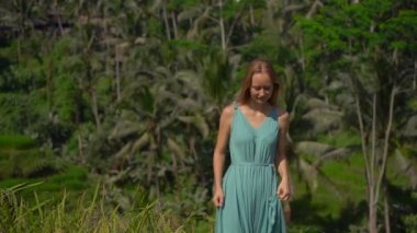 Mavi elbiseli güzel bir genç kadının yavaş çekimleri Bali adasındaki Ubud köyündeki ünlü Tegalalang Rice Teraslarını ziyaret ediyor.