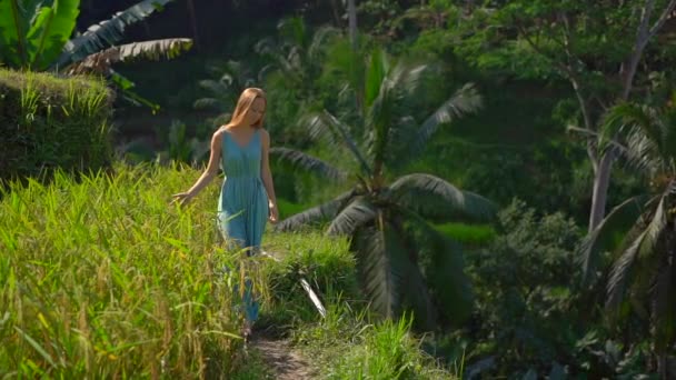 Slowmotion πλάνο μιας όμορφης νεαρής γυναίκας με μπλε φόρεμα επισκέπτεται διάσημους Tegalalang Rice Terraces στο χωριό Ubud στο νησί Μπαλί — Αρχείο Βίντεο