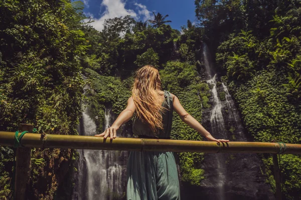 Kobieta w turkusowej sukience przy wodospadach Sekumpul w dżungli na wyspie Bali, Indonezja. Koncepcja podróży na Bali — Zdjęcie stockowe